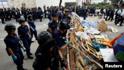 Polisi Hong Kong memindahkan barikade-barikade yang dipasang oleh para demonstran di komplek perkantoran pemerintah, Rabu (11/12).
