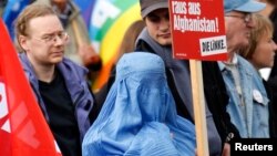 FILE - A protester dressed in traditional burqa garment attends a demonstration against the deployment of German armed forces in Afghanistan in front of the Brandenburg Gate in Berlin.