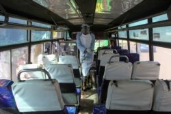 A man sprays disinfectant to sanitize a public bus against the spread of the new coronavirus, in downtown Nairobi, Kenya, March 19, 2020.