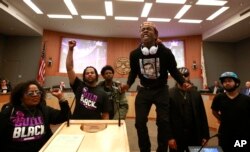Stevante Clark stands on a desk as he shouts the name of his brother Stephon Clark, who was fatally shot by police a week earlier, during a meeting of the Sacramento City Council in Sacramento, California, March 27, 2018.