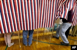 FILE - A voter enters a booth at a polling place in Exeter, N.H., Nov. 8, 2016. Donald Trump won the presidency, even as he lost the popular vote to Democrat Hillary Clinton. He nonetheless tweeted on Nov. 26 that he won the popular vote. and alleged there was “serious voter fraud” in California, New Hampshire and Virginia. There’s no evidence to back up those claims.