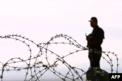 FILE - An Iranian guard stands on a mound at Mirjaveh point, where the borders of Iran, Afghanistan and Pakistan meet, Dec. 2, 2003.