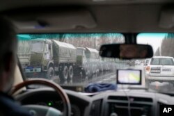 In this OSCE monitoring mission photo taken Nov. 21, 2017, in Ukraine's eastern city of Luhansk, armored personnel carriers and armed men drive in the city center. Dozens of armed people in combat fatigues deployed Nov. 22 to main administrative buildings in Luhansk, a major city in rebel-controlled territories in eastern Ukraine, in a sign of a split in the rebel leadership.