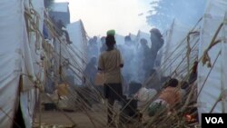 Cooking fires cloud the air with smoke around the maze of tents.