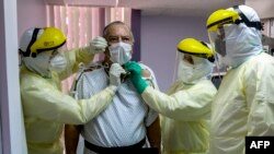 FILE - In Panama, a patient with a confirmed case of COVID-19, is surrounded by a medical team at the intensive care unit of Paitilla Hospital in Panama City, May 6, 2020.