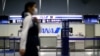 FILE - An employee, wearing protective mask following an outbreak of the coronavirus disease (COVID-19), passes in front of an All Nippon Airways (ANA) counter at the almost empty Kansai International Airport in Osaka, Japan, March 14, 2020. 