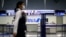 FILE - An employee, wearing protective mask following an outbreak of the coronavirus disease (COVID-19), passes in front of an All Nippon Airways (ANA) counter at the almost empty Kansai International Airport in Osaka, Japan, March 14, 2020. 