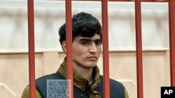 বাসমানি জেলা আদালতের প্রেস সার্ভিস দ্বারা প্রকাশিত ছবিতে, ক্রোকাস সিটি হলের গুলিচালনার ঘটনায় একজন সন্দেহভাজন ঝুমোখোন কুরবোনভ রাশিয়ার মস্কোর আদালতে একটি খাঁচায় দাঁড়িয়ে আছেন, ২৭ এপ্রিল, ২০২৪। 