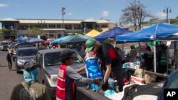 อาสาสมัครร่วมกันทำงานที่ศูนย์แจกจ่ายอาหาร ที่ลานจอดรถของห้างสรรพสินค้าแห่งหนึ่งในเมืองลาไฮนา ฮาวาย หลังไฟป่ารุนแรงทำลายหลายส่วนของเกาะเมาวี (AP)