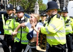 FILE - Police remove a climate change demonstrator during a march supported by Extinction Rebellion in London, Britain. May 24, 2019.