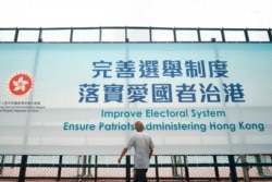 FILE - A man walks past a government advertisement promoting the new Hong Kong electoral system changes, in Hong Kong, March 30, 2021.