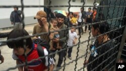Ethnic Uighur Muslims line up beside a police van in Khlong Hoi Khong of southern Songkhla province, Thailand, Mar. 15, 2014. 