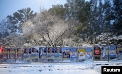 Electoral posters are seen during a heavy snowfall in Rome, Feb, 26, 2018.