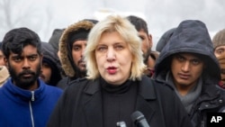 FILE - Surrounded by migrants, Dunja Mijatovic, the Council of Europe commissioner for human rights, addresses reporters at the Vucjak refugee camp outside Bihac, northwestern Bosnia, Dec. 3, 2019.