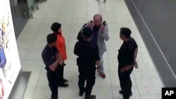 In this image made from airport closed circuit television video and provided by Fuji Television, Kim Jong Nam, exiled half-brother of North Korea's leader Kim Jong Un, gestures towards his face while talking to airport security and officials at Kuala Lump