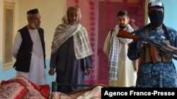 A Taliban fighter, right, and residents stand next to the bodies of civilians who were killed in an operation begun the night before by Taliban members against Islamic State Khorasan, the local chapter of the jihadist group, in Kandahar, Afghanistan, Nov. 15, 2021.