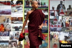 FILE - A Buddhist monk walks past anti-Muslim billboards inside the Masoeyein Monastery complex in Mandalay, Myanmar, Oct. 7, 2015.