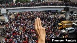 A demonstrator shows the three-finger salute as people rally in a protest against the military coup and to demand the release of elected leader Aung San Suu Kyi, in Yangon, Myanmar, Feb. 7, 2021.