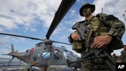 A member of the Philippine Naval Special Operations Group poses for photographers beside the Philippine Navy Agusta Westland 109 helicopter on board the BRP Gregorio Del Pilar (PF15) warship at Manila's pier, Dec. 17, 2014.