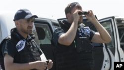 Members of OSCE mission to Ukraine examine the area of the Malaysia Airlines Flight 17 plane crash near the village of Hrabove, Donetsk region, eastern Ukraine Friday, Aug. 1, 2014.