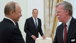 FILE - In this June 27, 2018 photo, Russian President Vladimir Putin, left, and U.S. National security adviser John Bolton greet each other as Russian Foreign Minister Sergey Lavrov looks on during their meeting in the Kremlin in Moscow.