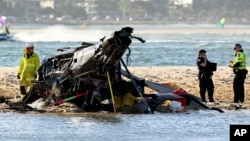 Emergency workers inspect a helicopter at a scene collision near Seaworld, on the Gold Coast, Australia, Jan. 2, 2023. 