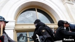 Un manifestante pro-Trump rompe una ventana en el Capitolio en Washington, D.C., el miércoles, 6 de enero de 2021.