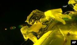 In this image made from video provided by NASA, U.S. astronauts Shane Kimbrough, left, and Peggy Whitson install a shield on a relocated docking port outside the International Space Station, March 30, 2017. An important piece of micrometeorite shielding was lost during the spacewalk at another part of the station earlier in the day.