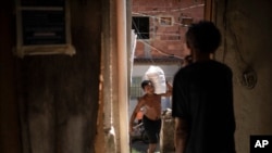 People carry food donated by the Rio de Paz NGO to be distributed to residents of the Mandela slum amid the COVID-19 pandemic in Rio de Janeiro, Brazil, March 27, 2021.