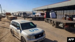 Mobil PBB melewati truk pengantar bantuan kemanusiaan yang memasuki Gaza melalui perbatasan Kerem Shalom (Karm Abu Salem) di bagian selatan wilayah Palestina, di Rafah, Jalur Gaza selatan, 17 Februari 2024. (SAID KHATIB/AFP)