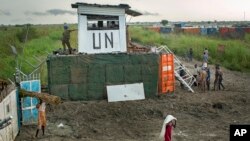 Displaced South Sudanese next to United Nations peacekeepers from Mongolia guarding the gate, at a camp at the United Nations Mission in South Sudan (UNMISS) base in the town of Bentiu, South Sudan, Sept. 22, 2014. 