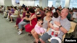 Couples from the U.S. wait at the U.S. embassy to get visa packs for their newly adopted Chinese children in Guangzhou, south China's Guangdong province, May 30, 2007.