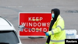 A NHS worker passes a COVID-19 test kit to a driver at a mobile test center, amid the coronavirus outbreak, in Broxbourne, Hertfordshire, Britain, Feb. 2, 2021. 