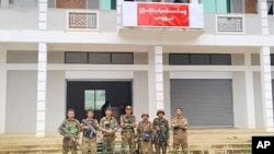 FILE - Members of the Ta'ang National Liberation Army and Mandalay People's Defense Force pose for a photograph in front of a captured building in Nawnghkio township, Shan state, June 26, 2024. (Mandalay People's Defense Force via AP)