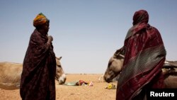 Women wait to load their carts with bags of rice and bottles of cooking oil at a food distribution center run by the Spanish NGO Accion contra el Hambre (Action Against Hunger) in Tarenguel, Gorgol region, Mauritania, May 30, 2012.