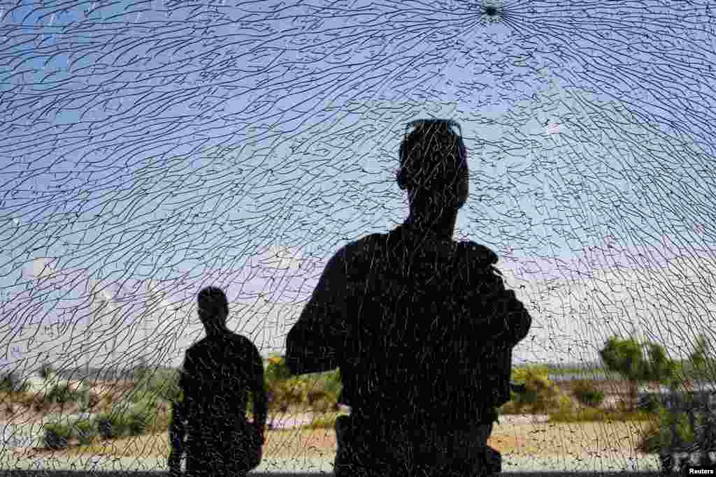 Israeli security personnel look at a window damaged by shrapnel after a short-range rocket landed&nbsp; near the Erez Crossing, a pedestrian/cargo terminal on the Israeli Gaza Strip barrier, July 16, 2014.