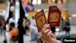 Seorang demonstran pro-demokrasi memegang paspor British National Overseas (BNO) saat berlangsungnya aksi protes menentang UU Keamanan Nasional baru di Hong Kong, 1 Juni 2020. (REUTERS / Tyrone Siu)