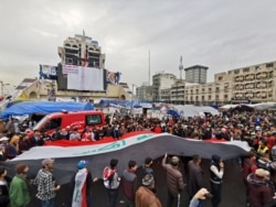 Iraqi demonstrators carry an Iraqi flag during anti-government protests in Baghdad, Dec. 27, 2019.