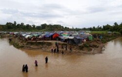 FILE - Rohingya refugees cross a stream to reach their temporary shelters at No Man's Land between the Bangladesh-Myanmar border, at Cox's Bazar, Bangladesh, Sept. 9, 2017.