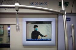 A public service announcement that encourages people to wear face masks plays on a subway train during the morning rush hour in Beijing, Feb. 3, 2020.