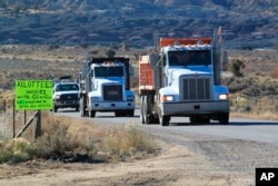 Oilfield trucks drive along the road that leads toward Chaco Culture National Historical Park in northwestern New Mexico on Monday, Nov. 22, 2021. Navajo allottees say their livelihoods depend on oil and gas development.