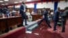 A lawmaker steps over a large puddle of water on the Parliament floor, created by rain water leaking through the roof, as lawmakers meet to debate whether or not to start impeachment proceedings for Haitian President Jovenel Moise in Port-au-Prince, Haiti