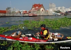 FILE - A volunteer rows his kayak as he collects trash in the Chao Praya river to raise public awareness on the damage single-use plastic has on the environment in Bangkok, Thailand, Dec. 21, 2018.