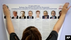 A polling station employee hangs a list of candidates for the 2018 Russian presidential election during preparations for the election at a polling station in St.Petersburg, Russia, March 16, 2018. The presidential elections will be in Russia March 18, 2018.