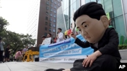 FILE - A South Korean university student wearing a mask depicting North Korean leader Kim Jong Un performs during a gathering to welcome the opening of the U.N. human rights office in Seoul, South Korea. A U.N. Commission of Inquiry report last year detai
