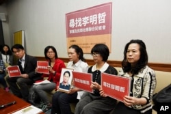 In this photo taken Friday, March 24, 2017, Lee Ching-yu, third from right holds up a photo of her missing husband and Taiwanese pro-democracy activist Lee Ming-che during a press conference with other representatives of non-governmental organizations cal