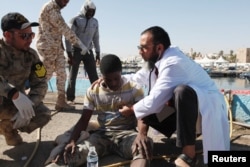 Migrants receive medical treatment in a port, after being rescued at sea by Libyan coast guard, in Tripoli, Libya, April 11, 2016.