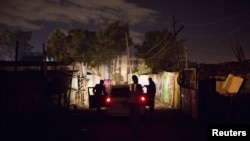 FILE - A man pleads with police officers to release a relative who they have just detained in Dandora during a night patrol in Nairobi, Kenya, Oct. 31, 2015. 