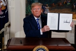 FILE - President Donald Trump shows a signed Presidential Memorandum after delivering a statement on the Iran nuclear deal from the Diplomatic Reception Room of the White House, May 8, 2018.