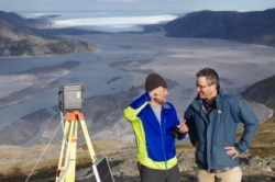 UCLA geography graduate student Lincoln Pitcher, left, and UCLA geography professor Laurence C. Smith overlook the Isortoq River, where meltwater leaves the Greenland ice sheet to flow to the ocean seen in the distance. (UCLA/Lawrence C. Smith)